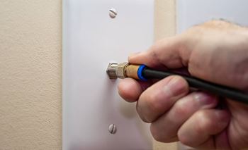 A person is screwing a light switch into a wall socket.